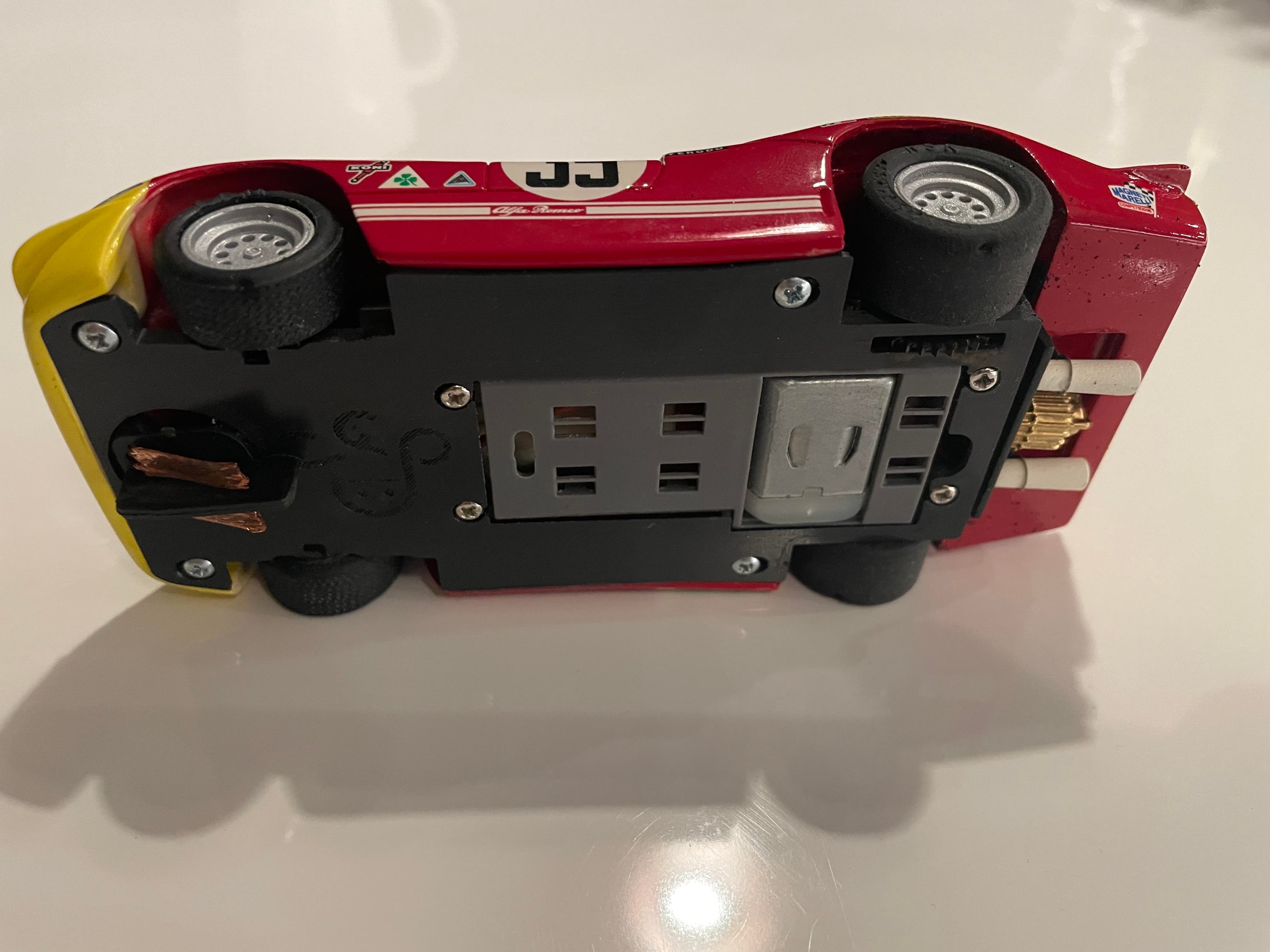 Dessous d'une voiture de circuit miniature rouge et jaune avec le numéro trente-trois.