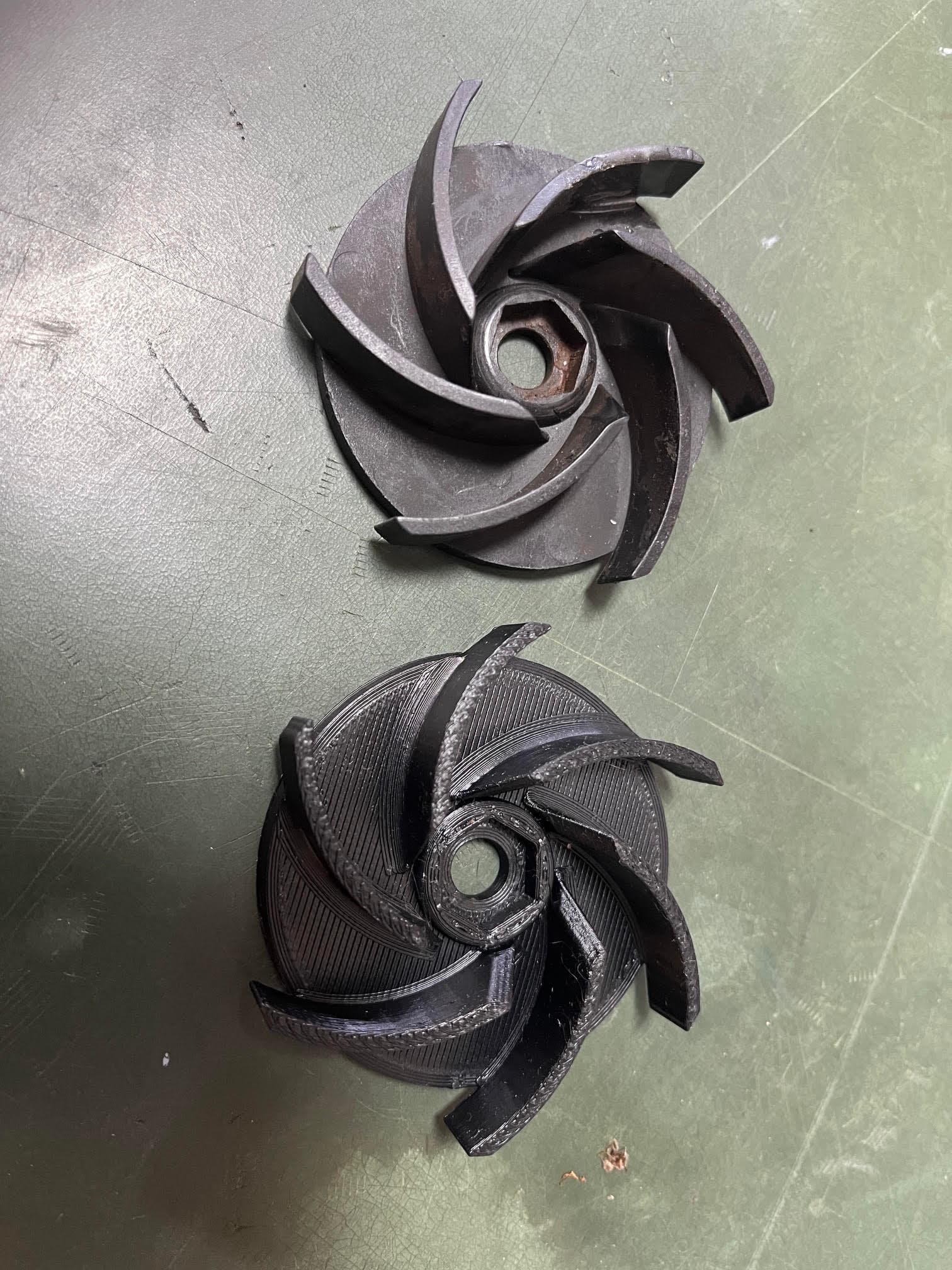 Deux turbines noires, une métallique usée et une imprimée en 3D, sur fond vert.