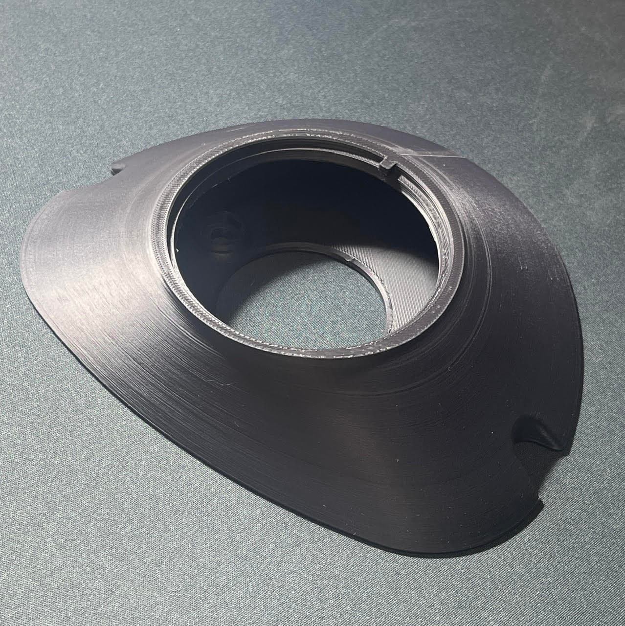 Pièce noire imprimée en 3D, de forme conique avec une large ouverture centrale circulaire.