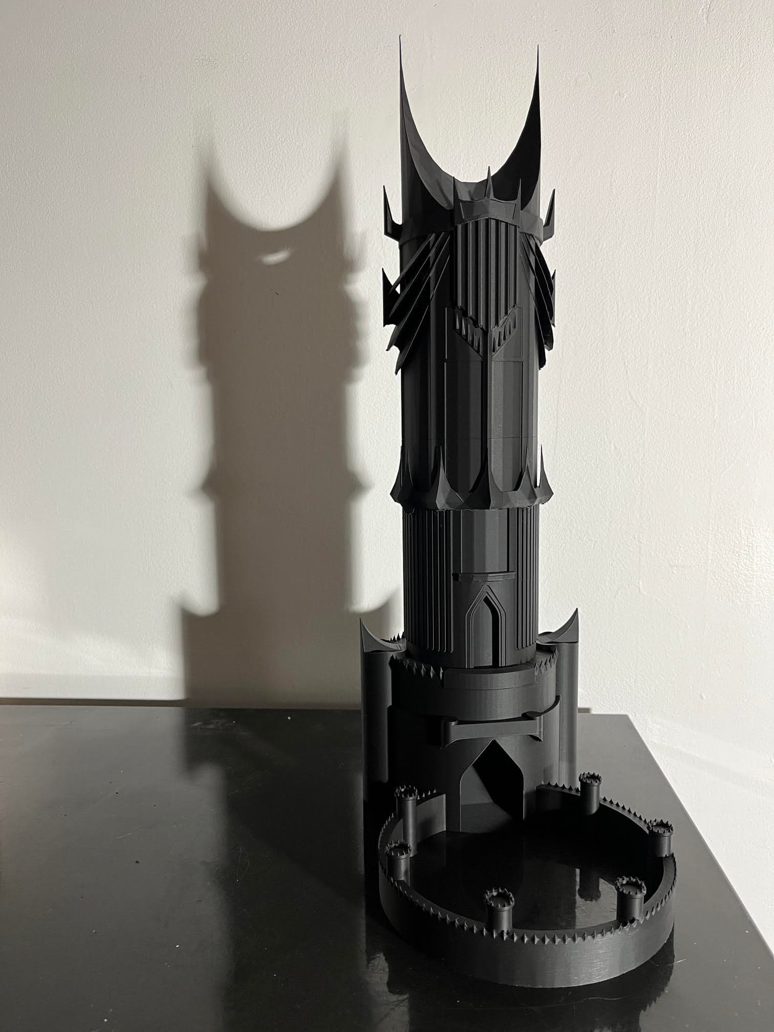 Tour à dés noire d'Orthanc imprimée en 3D projetant une ombre sur un mur.